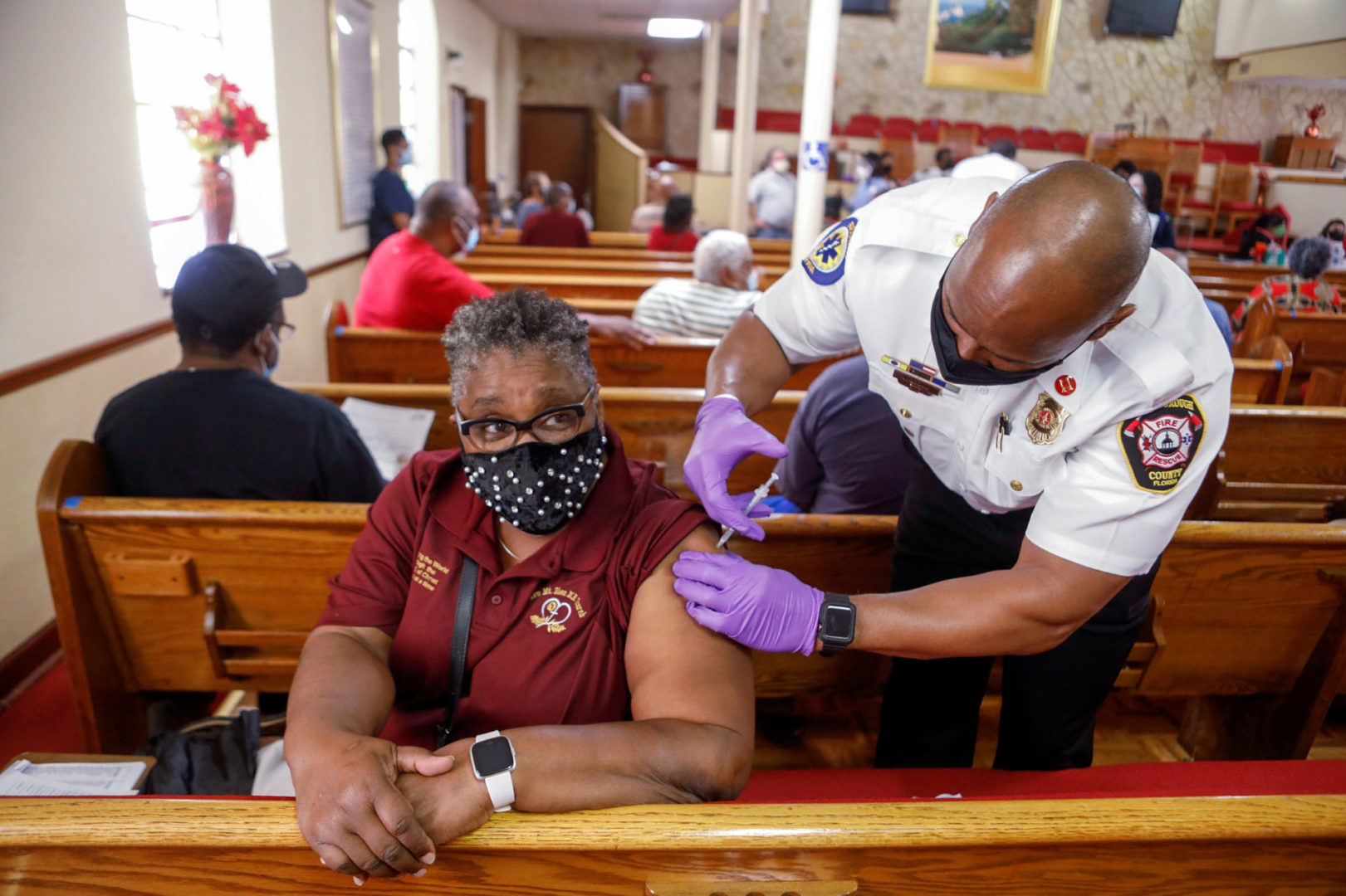 A woman receives the Pfizer-BioNTech COVID-19 vaccine  from a Hillsborough County Fire Rescue paramedic Neil Brown at the historic Greater Bethel Missionary Baptist Church in Tampa, Florida, U.S. February 14, 2021.  REUTERS/Octavio Jones